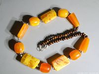 Top view of vintage Bakelite necklace showing large cube and rounded orange-yellow beads alternating with small dark brown beads and metal clasp.