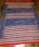 Full view of vintage hand woven tribal rug showing overall pattern, colors, and edges.
