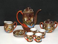 Complete vintage Imperial Satsuma tea/coffee set with coffee pot, sugar bowl, creamer, 4 cups and saucers, all hand painted with colorful human figures on brown.