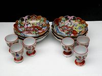 Full view showing six hand painted scalloped bowls stacked and six matching egg cups arranged in front