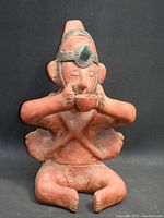 Front view of the terracotta seated human figure vessel holding a bowl.