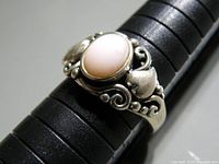 Front angle showing pink oval gemstone and sterling silver scrollwork band.
