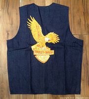 Full view of the back of the dark blue denim vest showing large embroidered golden eagle and Harley Davidson Motor Cycles logo.