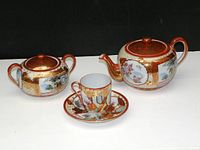 Full view of vintage Japanese Kutani porcelain tea set including teapot, sugar bowl, teacup, and saucer with ornate traditional multicolor and gold design.