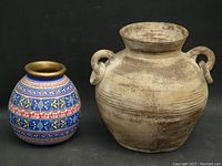 Close-up of large rustic earthenware jar and small colorful ceramic vase