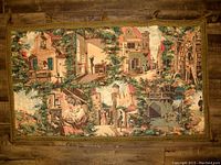 Full view of the vintage tapestry showing various village scenes with buildings and people in a scenic layout