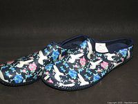 Pair of navy rubber clogs with hummingbird and floral pattern, viewed from the side and angled showing the design and shape.