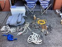 Photo showing two folding chairs, Igloo cooler, gray boat cover, multiple ropes and cords, boat steering wheel and marine hardware.