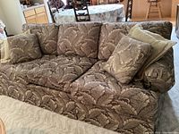 Front angle showing the detailed leaf pattern fabric, seat cushions, and matching throw pillows.