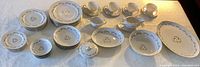Full view of the vintage Kyoto Fine China set showing plates, cups, bowls, platter, gravy boat, and covered serving bowl arranged on table.