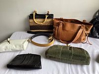 Photo showing most of the handbags and suede belt on a white surface with wall background.