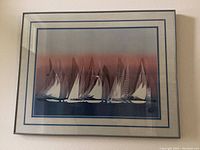 Framed print of sailboats showing multiple sailboats with various sails on water with a dusk sky, double-lined blue mat and black frame.
