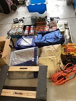 Photo showing tarps, extension cords, cans of spray, and furniture dolly.