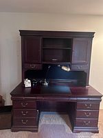 Front view of the vintage solid wood desk with attached hutch, showing multiple drawers, drawers with locks, and a dark finish.