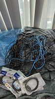 Photo showing tangled black and blue Ethernet cables with packaged HDMI cables and loose shorter HDMI cable.