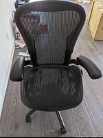 Front view of black mesh seat, adjustable armrests and five-star caster base