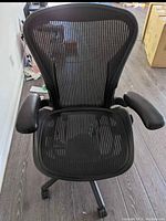 Front view showing mesh seat, back, armrests, base with casters