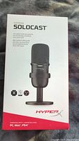 Front view of the box showing the HyperX SoloCast microphone image, product name, and compatibility details.