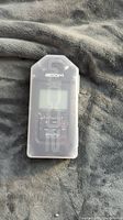 Closed Zoom H4n Pro audio recorder in protective plastic case on grey surface.