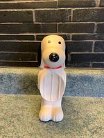 Front view of the Snoopy dish soap holder showing the elongated oval soap groove, Snoopy figure with red collar, black ears, and nose.