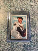 Front view of the 1952 Dave Koslo baseball card showing the player's illustrated pitching pose, the New York Giants uniform, and background with clouds.