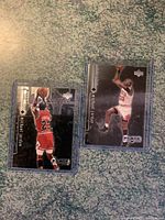 Two Michael Jordan Upper Deck Black Diamond basketball cards in protective sleeves on a textured surface.