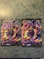 Photo showing the four regular-sized cards arranged to form the Morpeko Vunion jumbo card and an additional regular-sized Morpeko V card all laid out flat on a green textured surface.