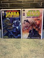 Two Star Wars comic books: Jabba the Hutt and Dark Empire II in protective sleeves placed side by side on a stone background.