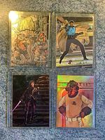 Four Star Wars cards in protective sleeves, showing two foil Ewok cards, Lando Calrissian holographic card, Luke Skywalker holographic card, and Rebel soldier holographic card