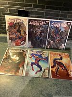 Photo showing all six Amazing Spider-Man comics in a single view on a green carpet. Covers are brightly colored and bagged for protection.