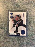Front image of Wayne Gretzky limited edition hockey card with player in black uniform, number 99, encased in clear plastic sleeve.