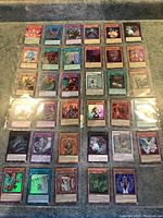 Photo of 35 Yugioh holographic trading cards arranged in a grid inside plastic protective sleeves.