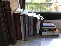 Books displayed on a windowsill showing spines and some covers, titles and authors visible to identify genre and titles.