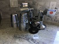 Full view of the kitchen cutter main unit and 4 metal drum attachments on counter