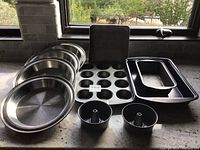 Overall view showing four stainless steel round pie pans, two 12-cup muffin tins, two mini bundt pans, rectangular cake pan and Wilton loaf pan.