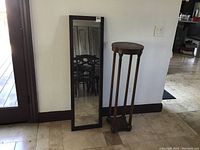 Photo showing full-length mirror standing against the wall next to the wooden plant stand.