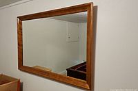 Full view of large rectangular wooden framed mirror hanging on wall