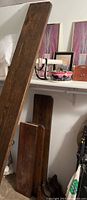 Wood shelves leaning against a wall near other household items.