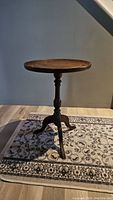 Full view of vintage round wooden decorative table with carved pedestal base and three legs