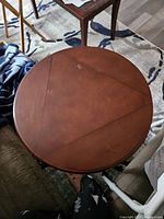 Top view showing round wooden table surface composed of three segments with seams, allowing conversion to triangular shape.