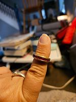 Ring shown on thumb displaying ruby stones on one side of the thick band.