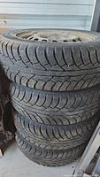 Stack of four winter tires on rims showing tread design and condition