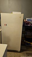 Front view of white upright freezer, plain exterior with Maytag label and stickers visible.
