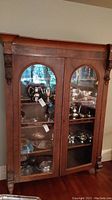 Front view of wood china cabinet filled with silverware showing double glass doors and interior shelves