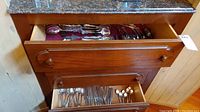 Two wooden drawers filled with assorted flatware including spoons, forks, and knives.