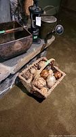 Woven wood basket with vine and wood balls, metal watering can, cast iron pump, wood basket with emblem on stone hearth