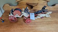 Side view of vintage cast iron toy fire engine horse-drawn cart with attached horses and two driver figures