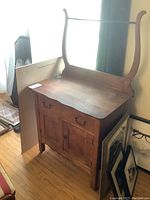 Full view of antique solid wood washstand showing single dovetailed drawer and two doors, with attached harp and towel rack on top.