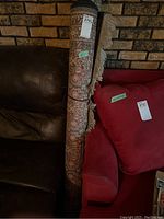 Rolled-up rug with visible tag and fringe, leaning between chair and sofa in living room
