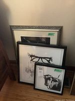 Four framed black and white art prints leaning against the wall with various sizes and styles.